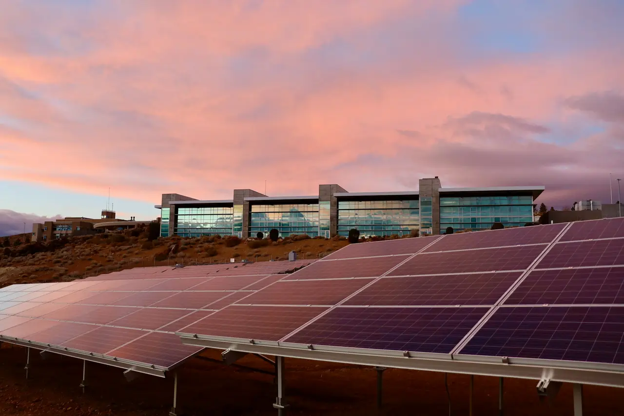 Edifício corporativo com painéis solares na cobertura sob um céu rosado de fim de tarde