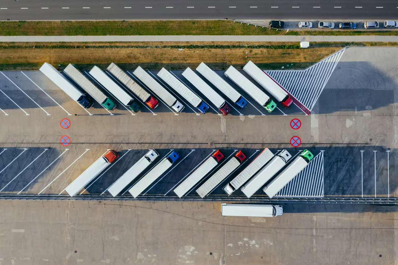 Vista aérea de um pátio logístico com caminhões estacionados lado a lado