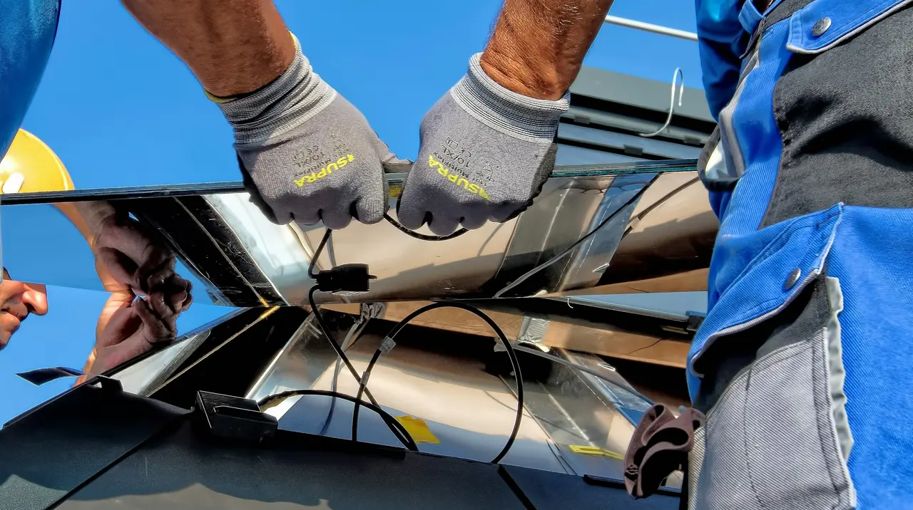 Mãos com luvas de um instalador fixando os cabos de um sistema solar