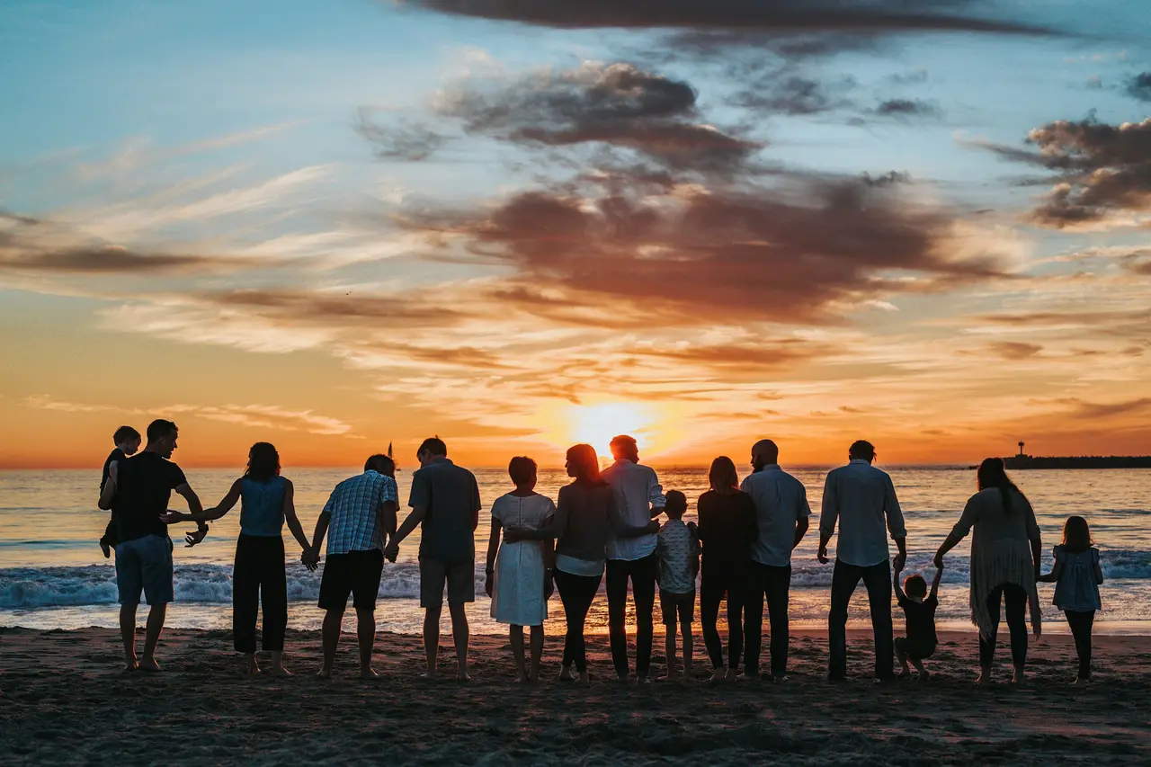 Família de mãos dadas diante de um campo dourado ao pôr do sol