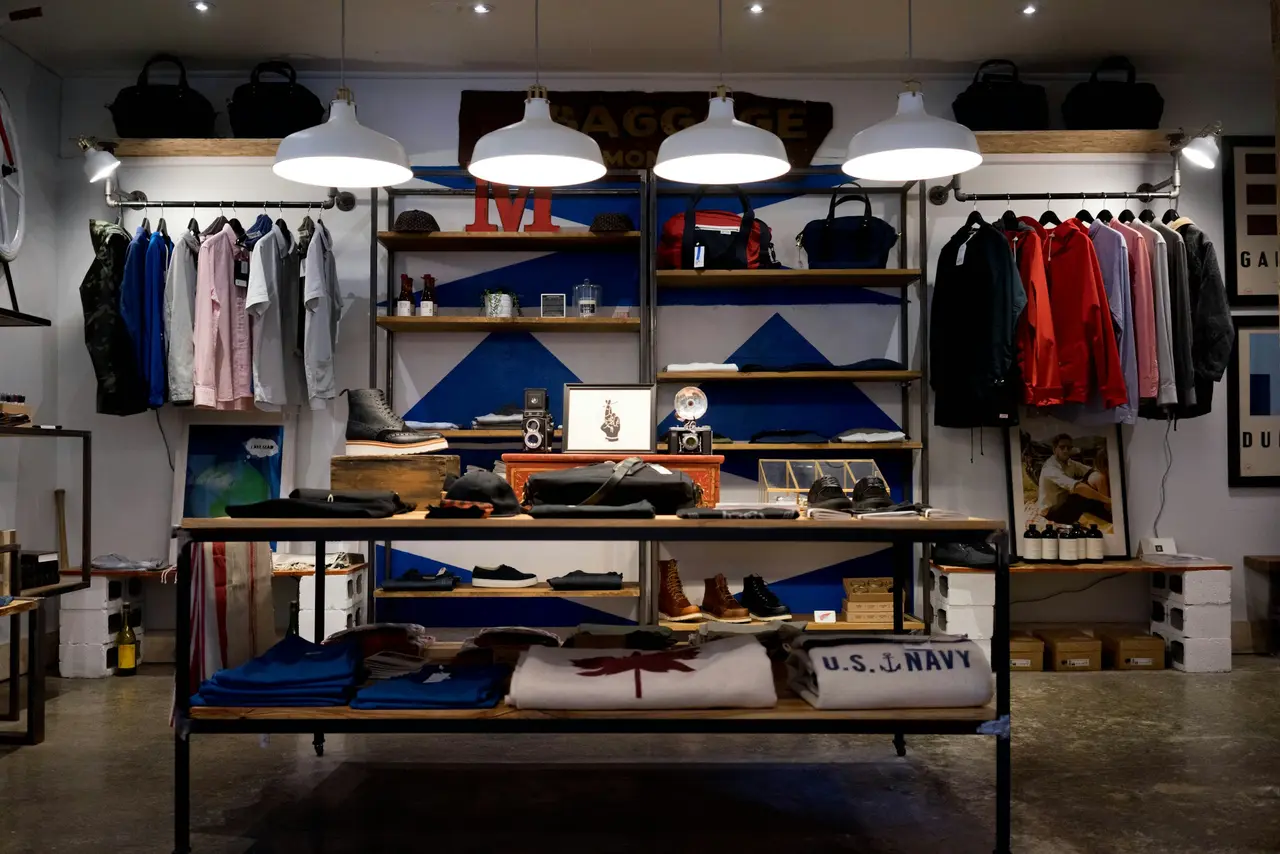 Interior de uma loja de roupas com prateleiras de madeira e luminárias