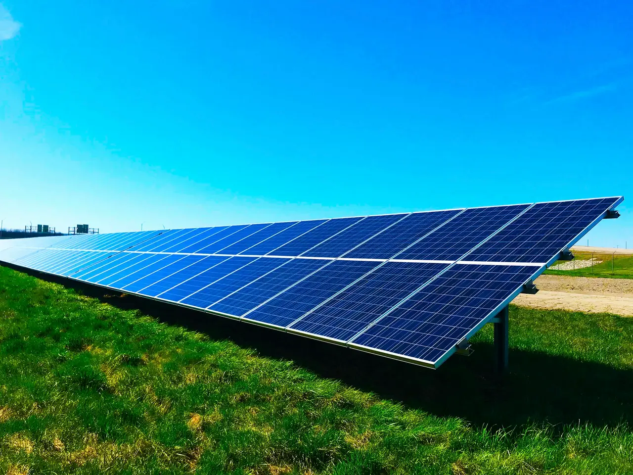 Painéis solares inclinados em fila sobre um gramado verde